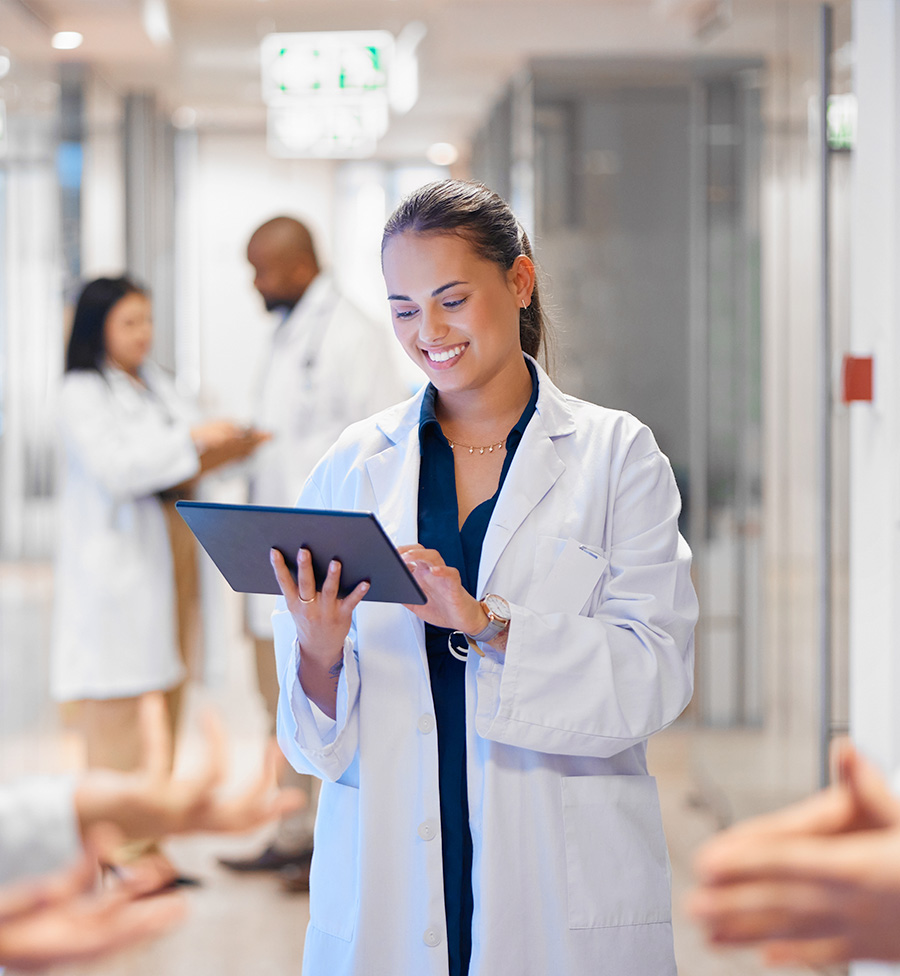 Scientist in lab coat looking on at a tablet.